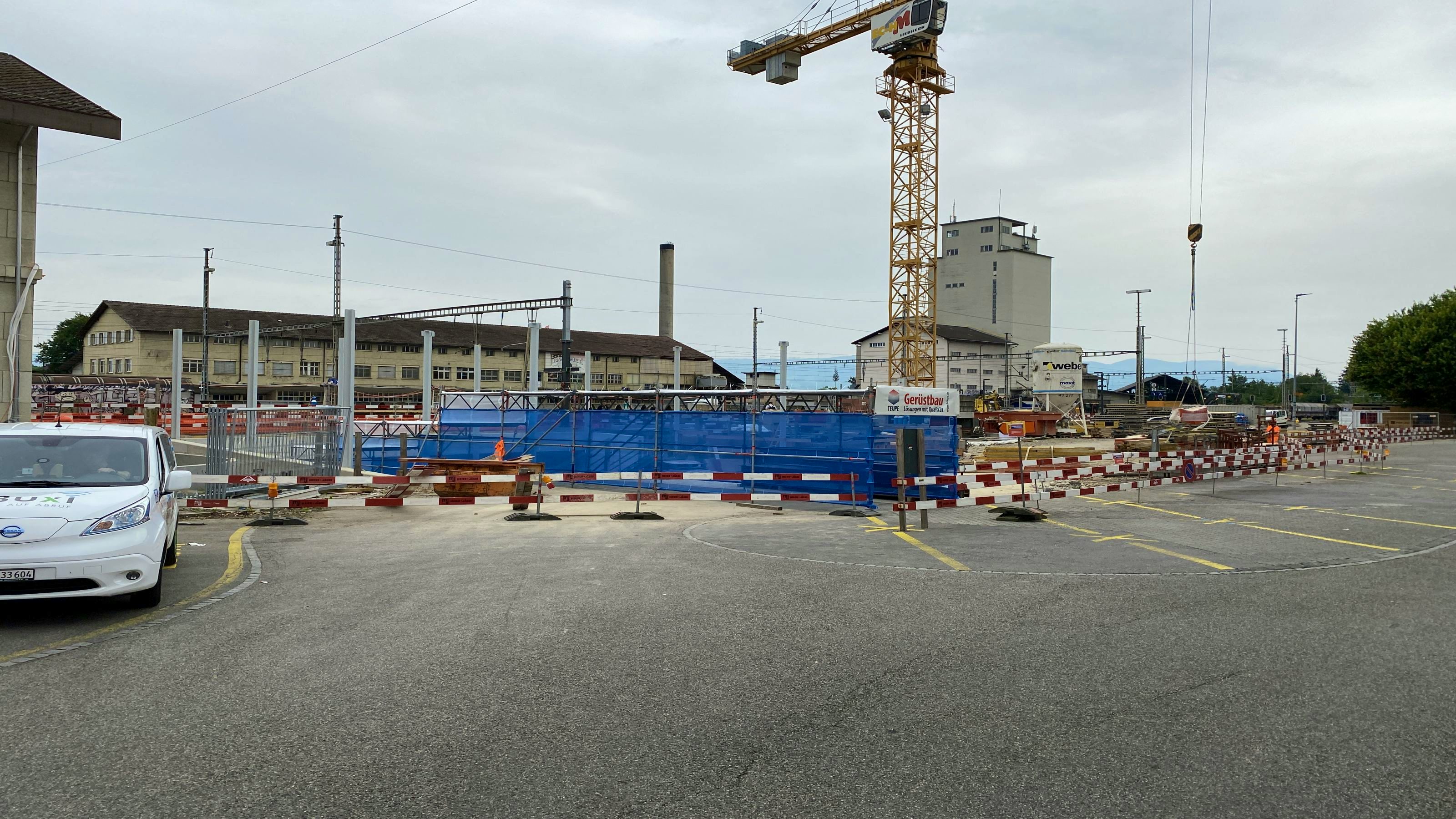 Vorübergehender Zugang zur Personenunterführung über einen Gerüsttunnel, um das Dach des Kundenzentrums auf die Stützen zu montieren.
