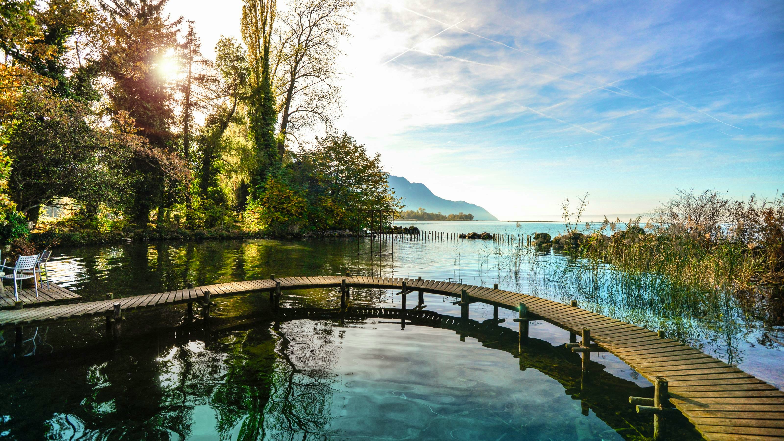 A wooden footbridge runs in a semi-circle along the shore of the lake.