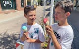 Two boys eating ice cream in a cone. 