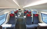 1st class interior – to the right of the aisle there are compartments to seat four and to the left there are compartments to seat two. The seat cushions are dark grey with a small red pillow attached to the headrest.